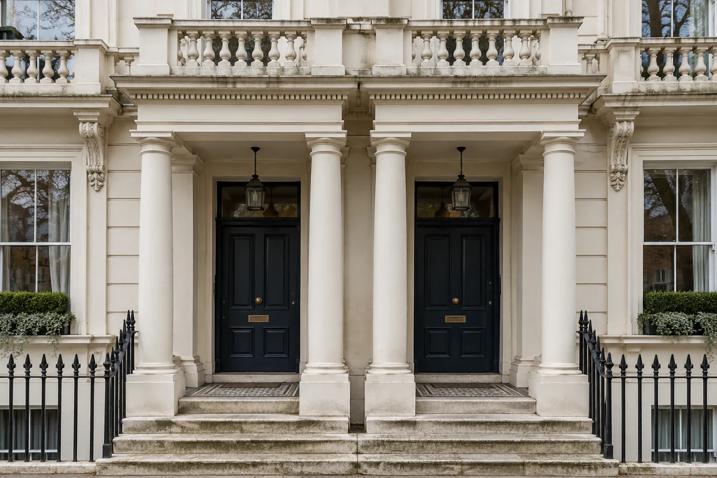 Paired stucco porticoes beneath a balustraded balcony on a tall cream terrace